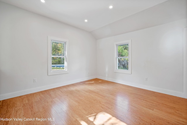 unfurnished room with vaulted ceiling and light wood-type flooring