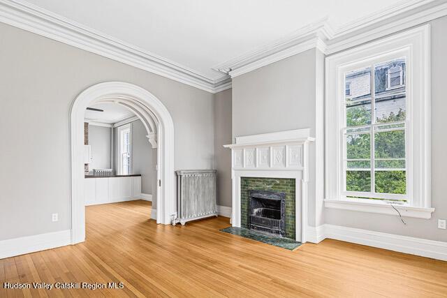 unfurnished living room with hardwood / wood-style floors, plenty of natural light, and crown molding