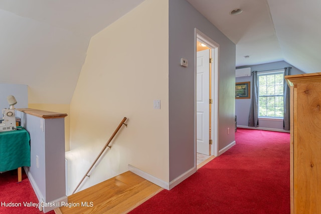 corridor featuring carpet flooring, lofted ceiling, and an AC wall unit