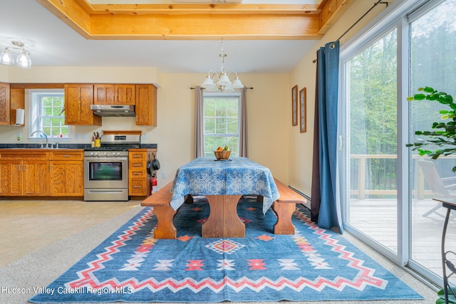 kitchen with stainless steel gas stove, sink, pendant lighting, light colored carpet, and a chandelier