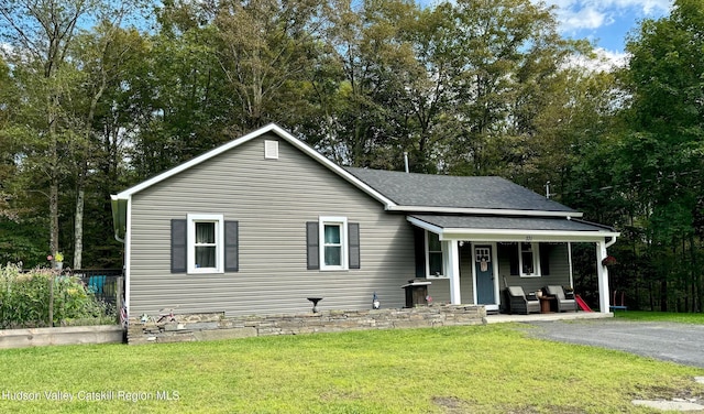 view of front facade with covered porch, a shingled roof, and a front lawn