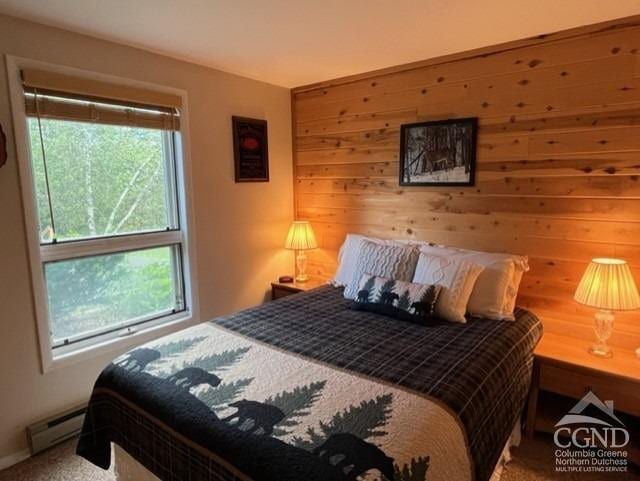 75 Highlands Dr Unit T-4, Hunter, NY 12442 - carpeted bedroom featuring multiple windows, a baseboard radiator, and wooden walls