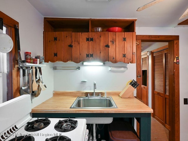 kitchen with white stove, light hardwood / wood-style floors, and sink