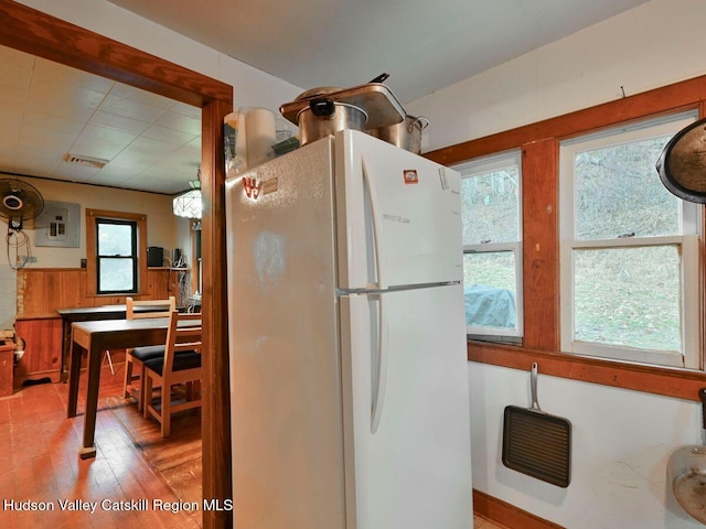 kitchen featuring hardwood / wood-style flooring, plenty of natural light, white fridge, and wood walls