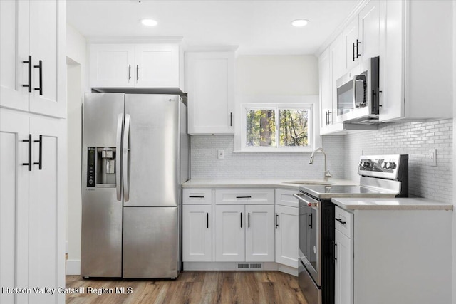 603-607 Old Stage Rd, Saugerties, NY 12477 - kitchen featuring stainless steel appliances, a sink, white cabinets, light countertops, and backsplash