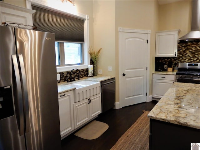 kitchen with appliances with stainless steel finishes, backsplash, light stone countertops, wall chimney range hood, and white cabinetry