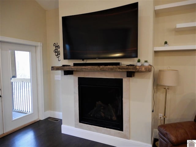 interior details featuring dark hardwood / wood-style floors and a tiled fireplace