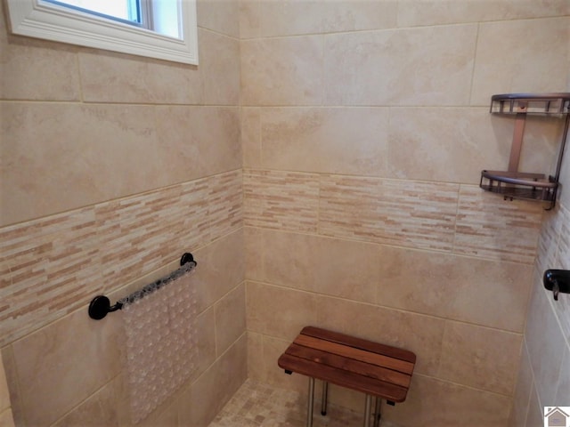 bathroom featuring a tile shower and tile walls