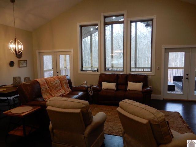 living room with dark hardwood / wood-style floors, vaulted ceiling, a notable chandelier, and french doors