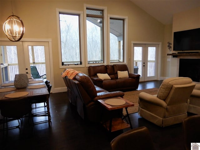 living room with dark hardwood / wood-style flooring, a notable chandelier, vaulted ceiling, and french doors