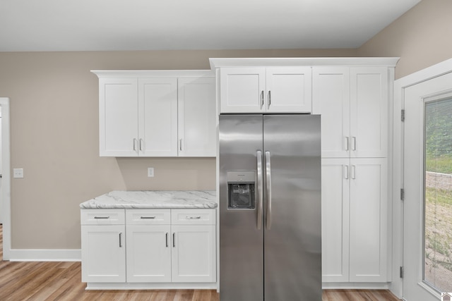 kitchen featuring stainless steel fridge with ice dispenser, light stone counters, white cabinetry, and light hardwood / wood-style flooring