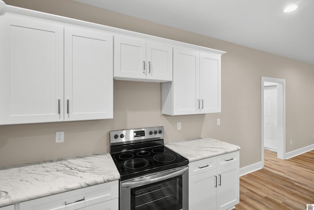 kitchen featuring white cabinets, light stone countertops, light hardwood / wood-style flooring, and stainless steel electric stove