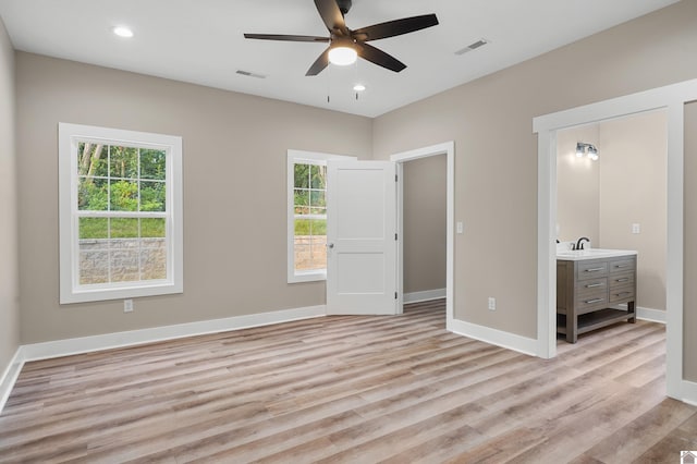 unfurnished bedroom with ceiling fan, sink, and light wood-type flooring