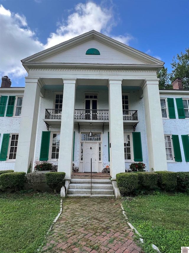 view of front facade featuring a balcony and a front yard