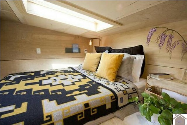 bedroom featuring wooden walls and vaulted ceiling