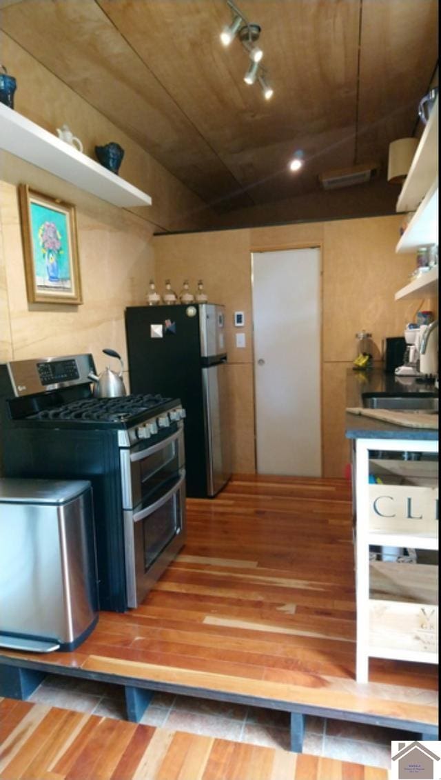 kitchen featuring track lighting, stainless steel appliances, wood ceiling, and wood-type flooring