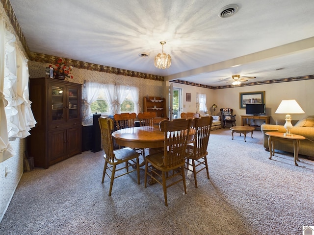 carpeted dining area featuring ceiling fan with notable chandelier