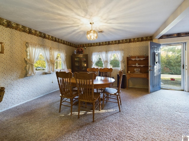 carpeted dining area featuring a notable chandelier and plenty of natural light