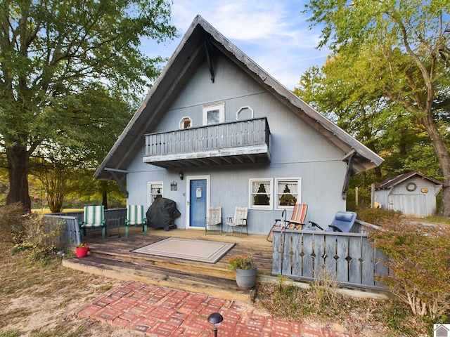 rear view of house with a wooden deck, a balcony, and a storage unit