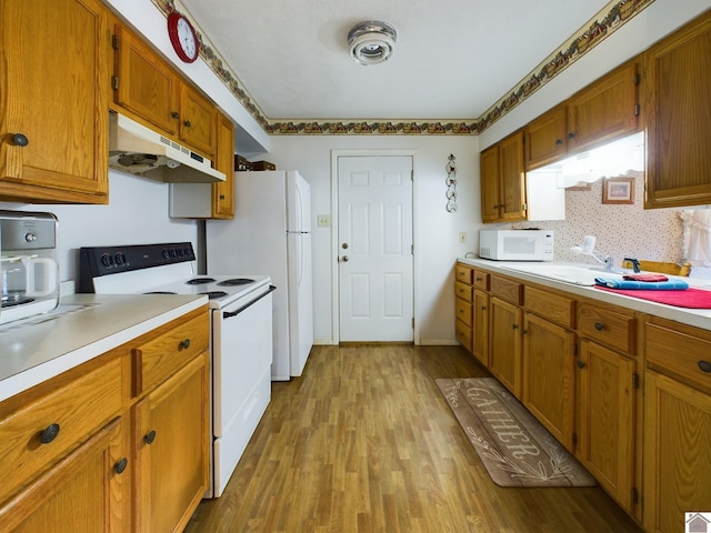 kitchen with white appliances, sink, and light hardwood / wood-style flooring