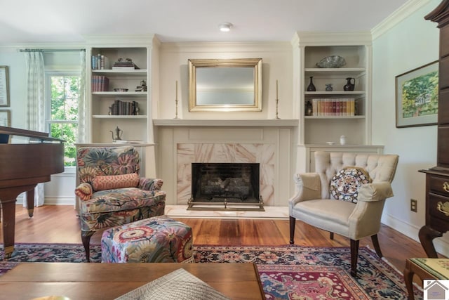 living area with ornamental molding, wood-type flooring, and a high end fireplace