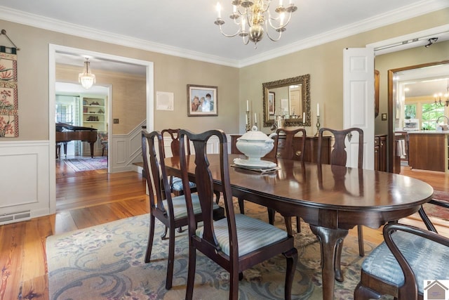 dining space with ornamental molding, an inviting chandelier, and hardwood / wood-style floors