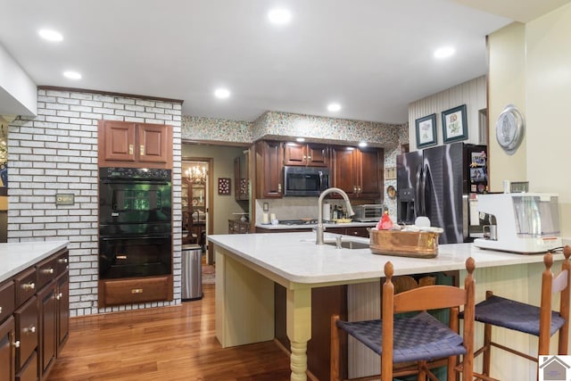 kitchen featuring decorative backsplash, a kitchen breakfast bar, stainless steel appliances, and light hardwood / wood-style floors