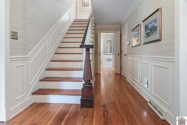 stairs with ornamental molding and wood-type flooring