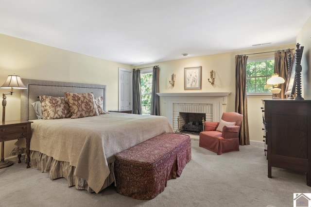 bedroom with multiple windows, a brick fireplace, and light colored carpet