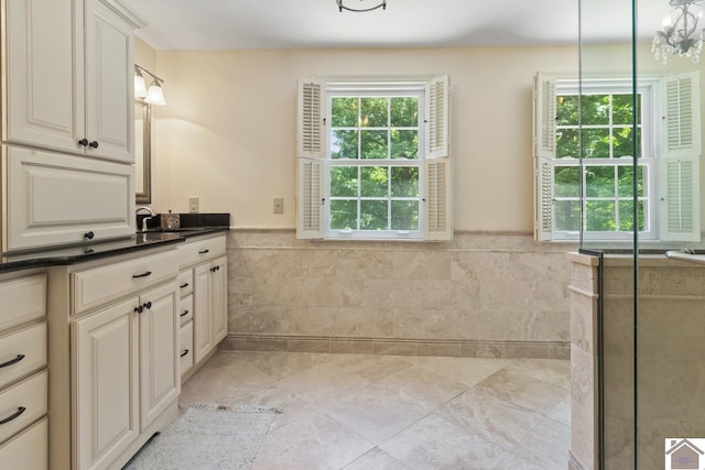 bathroom featuring an inviting chandelier, vanity, tile walls, and tile patterned floors