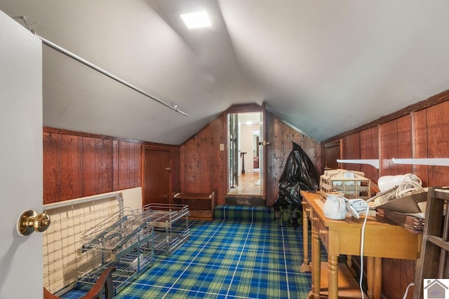 bonus room featuring wood walls, dark carpet, and vaulted ceiling