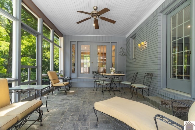 sunroom / solarium featuring ceiling fan, plenty of natural light, and wood ceiling