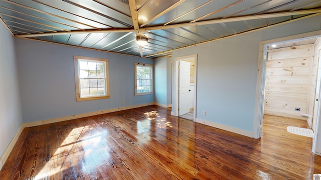 empty room with hardwood / wood-style flooring and lofted ceiling with beams