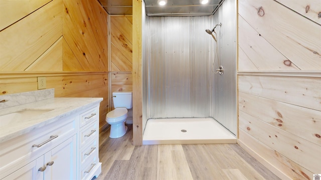 bathroom with vanity, wood-type flooring, toilet, wooden walls, and a shower