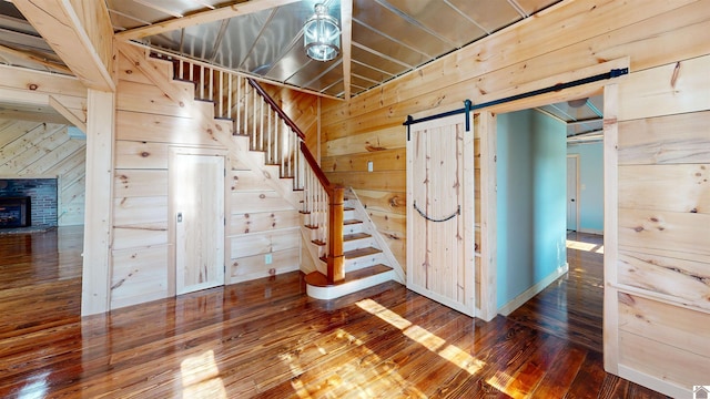 stairs featuring dark hardwood / wood-style floors, a fireplace, wooden walls, and a barn door