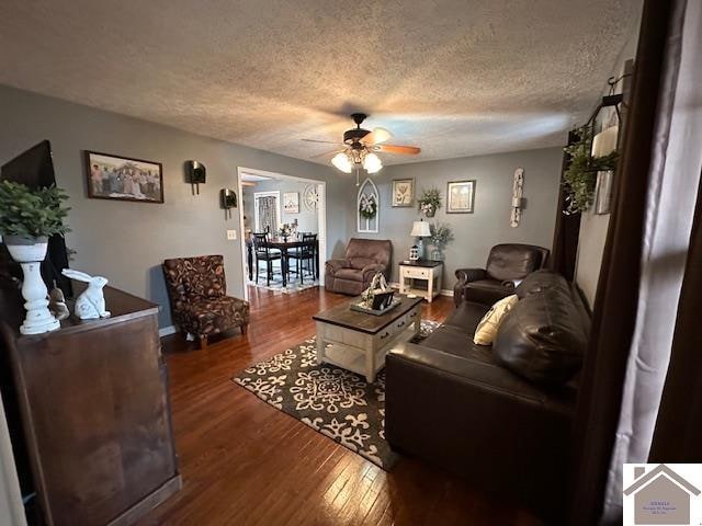 living room with dark hardwood / wood-style flooring, a textured ceiling, and ceiling fan