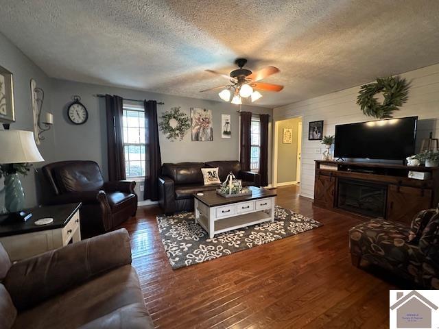 living room with a textured ceiling, ceiling fan, and dark hardwood / wood-style floors