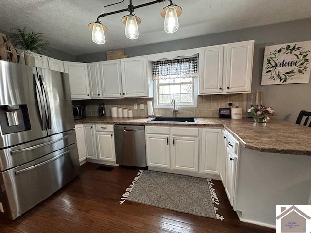 kitchen featuring dark hardwood / wood-style floors, appliances with stainless steel finishes, tasteful backsplash, decorative light fixtures, and white cabinetry