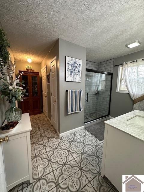 interior space featuring walk in shower, vanity, tile floors, and a textured ceiling