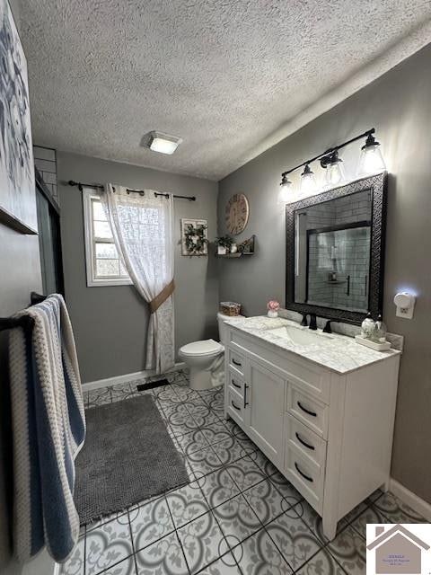 bathroom featuring a textured ceiling, tile floors, large vanity, and toilet