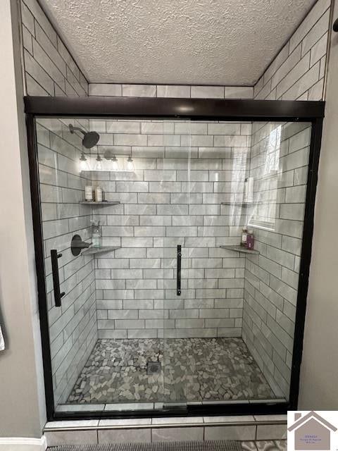 bathroom with an enclosed shower and a textured ceiling