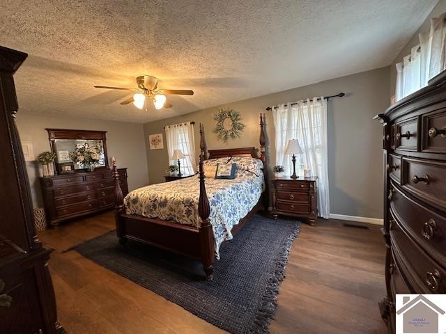 bedroom with a textured ceiling, multiple windows, ceiling fan, and dark hardwood / wood-style floors