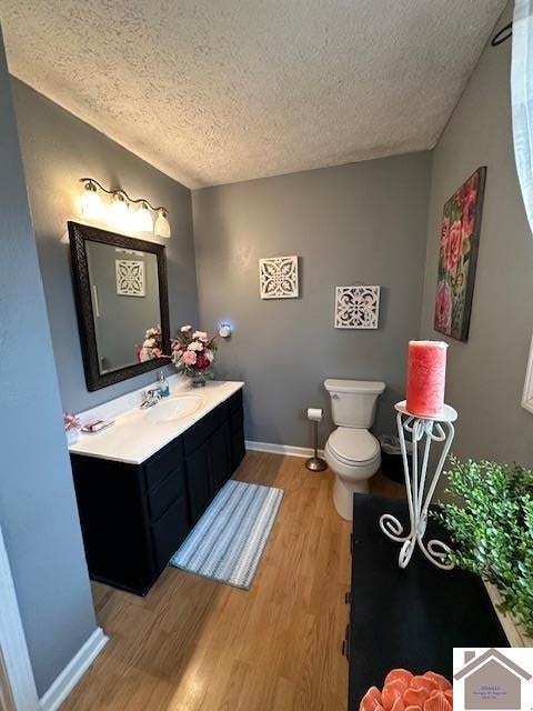 bathroom with a textured ceiling, vanity, toilet, and hardwood / wood-style flooring