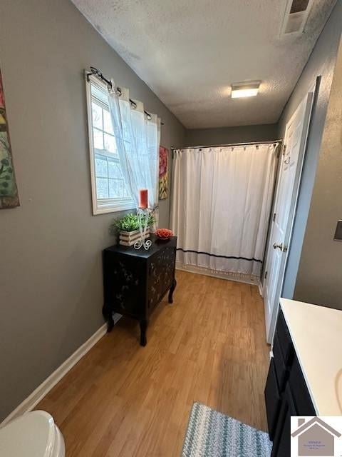 hallway featuring light hardwood / wood-style floors and a textured ceiling