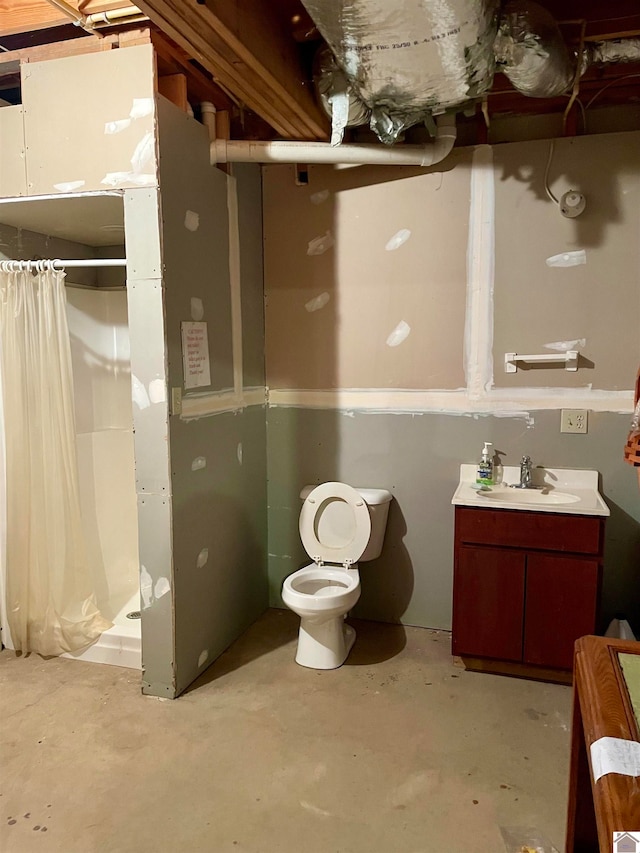 bathroom with toilet, concrete floors, curtained shower, and vanity