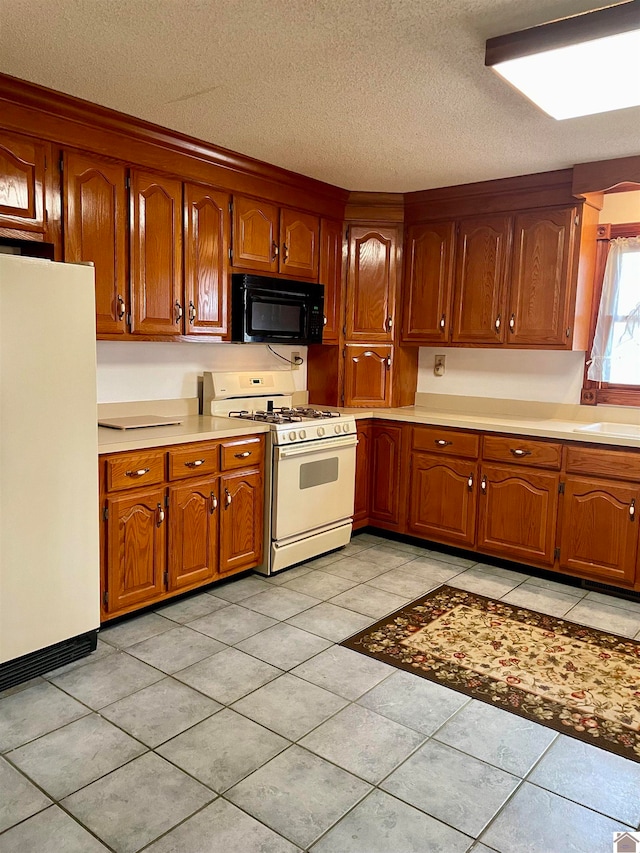 kitchen with white appliances, a textured ceiling, sink, and light tile floors