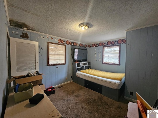 bedroom with a textured ceiling, dark colored carpet, and multiple windows