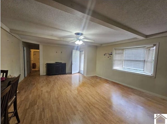 unfurnished living room with ceiling fan, beam ceiling, hardwood / wood-style flooring, and a textured ceiling