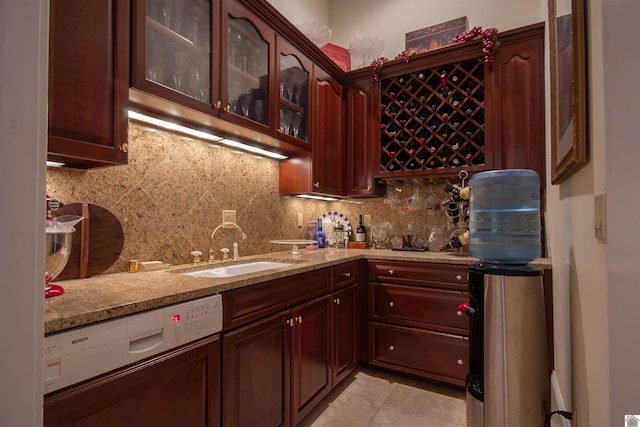 kitchen with light tile floors, white dishwasher, tasteful backsplash, and light stone counters