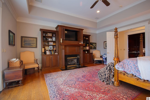 bedroom featuring crown molding, hardwood / wood-style floors, a raised ceiling, and ceiling fan